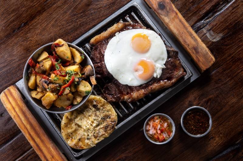 La especialidad de La Dorita son las carnes servidas en fuentes de hierro candente sobre tablas de madera