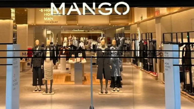 Escaparate y entrada de una tienda de ropa Mango con maniquíes vestidos a la moda y percheros de indumentaria al fondo