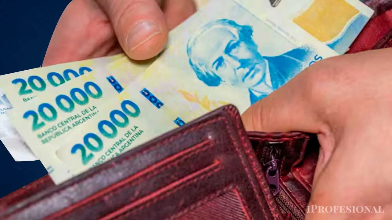 Una mano saca billetes de 20.000 pesos de una billetera