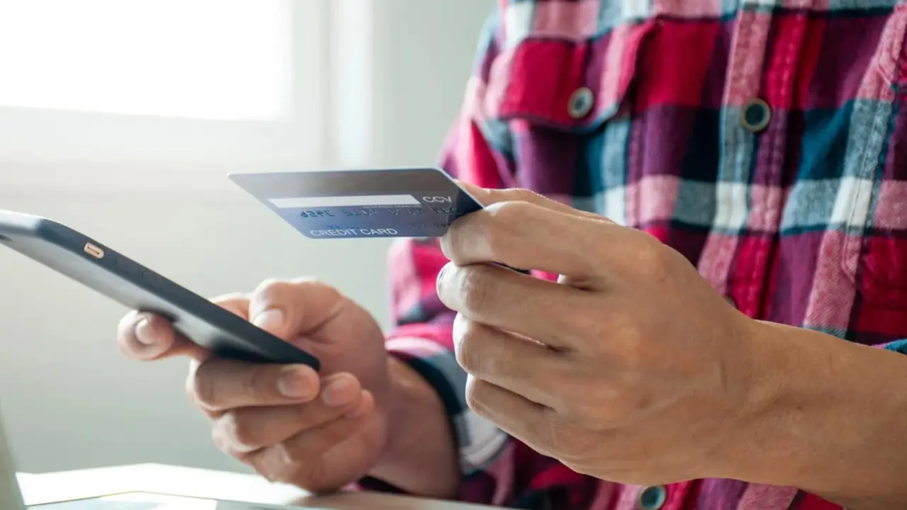 Un hombre con una tarjeta y un celular en la mano